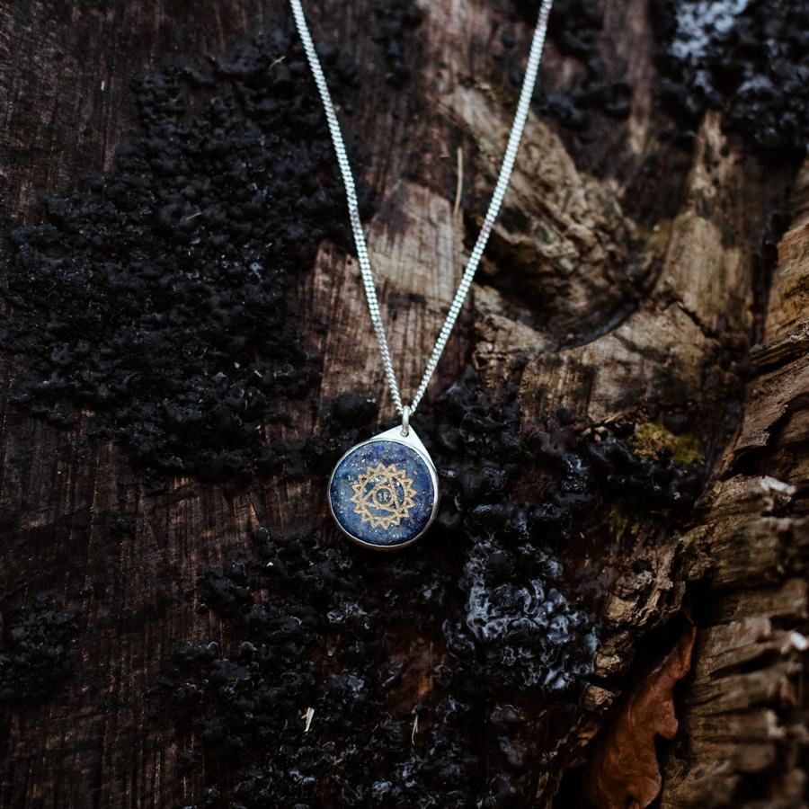 Engraved chakra amulet in 935 silver on dark bark
