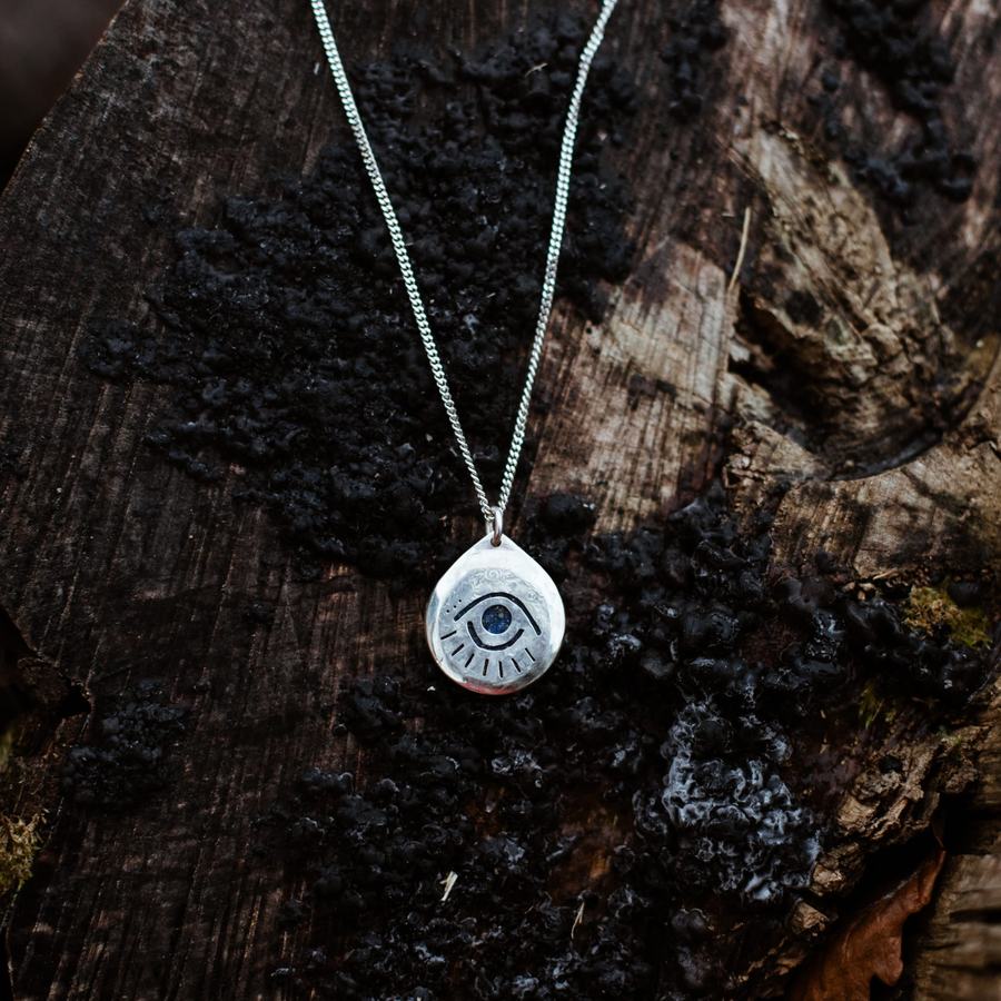 Guardian eye amulet in silver on dark wood